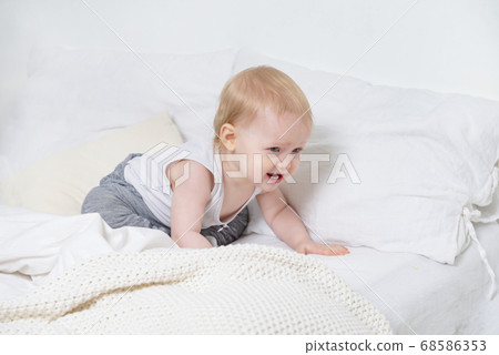 1 little girl in gray pants crying on the bed, sad 68586353