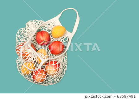 Peaches and apricots in eco bag on a blue background Peaches and apricots in eco bag on a blue background 68587491