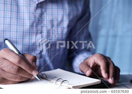 Close up of man hand writing on notepad. Close up of man hand writing on notepad. 68587680