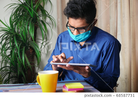Businessman in face mask working on digital tablet Businessman in face mask working on digital tablet 68587731