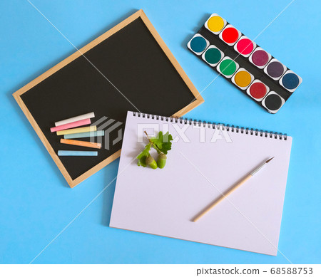 Back to school. Watercolors with white notebook and brush on blue background. Black school chart and chalks. Art concept. 68588753