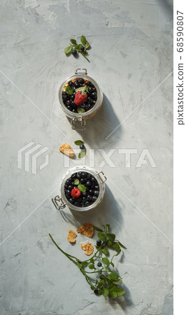 Desserts made from fresh berries in small glass jars. Layout on a grey background, vertically 68590807