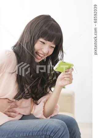 一個在智能手機上嘲笑視頻的女人 68592039