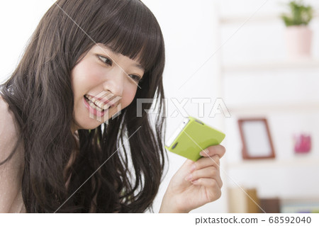 一個在智能手機上嘲笑視頻的女人 68592040