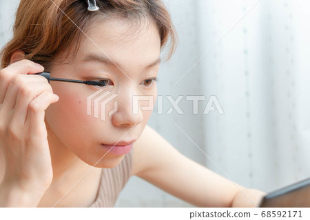 Woman doing mascara Woman doing mascara 68592171