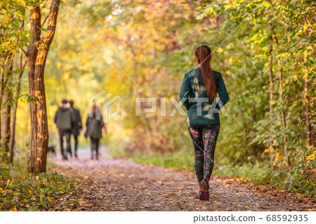 Woman walking in autumn forest nature path walk on trail woods background. Happy girl relaxing on active outdoor activity 68592935