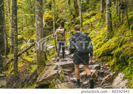 Hike couple hikers hiking forest trail in Autumn nature going camping with backpacks. Friends woman and man walking uphill on mountain in Quebec travel, Canada 68592945