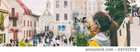 Quebec city old town tourist taking picture with mobile phone of famous wall art mural in Place Royale panoramic banner. Asian chinese woman on Autumn Canada travel 68592958