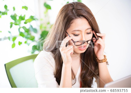 Young woman taking off her glasses at work 68593755