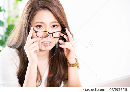 Young woman taking off her glasses at work Young woman taking off her glasses at work 68593756