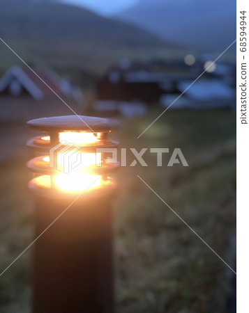 [Streetlight] Warm light | A road sign that illuminates a small village in the Faroe Islands (with copy space) 68594944