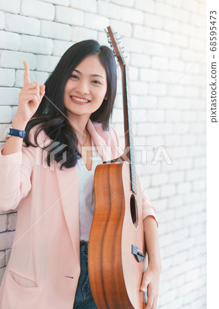 young woman playing guitar in living room, Enjoying carefree time at home. 68595473