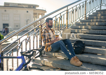 Man traveling on bicycle resting on the stairs Man traveling on bicycle resting on the stairs 68596352