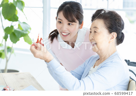 Nursing image Senior woman and caregiver folding origami Nursing image Senior woman and caregiver folding origami 68599417