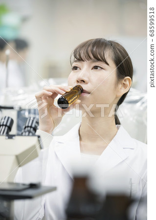 Young female researcher drinking energy drink between work 68599518