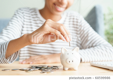 Hand of Asian young girl are putting coins in a piggy bank at home Hand of Asian young girl are putting coins in a piggy bank at home 68599986