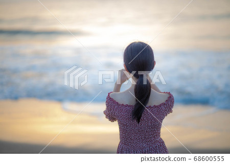 Woman taking a sunrise sunrise on the coast 68600555