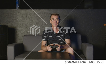 Joyful adult man playing video game alone entertaining at home enjoying gaming Joyful adult man playing video game alone entertaining at home enjoying gaming 68601536