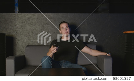 Guy sits on sofa and watches TV. Guy sits on sofa and watches TV. 68601537