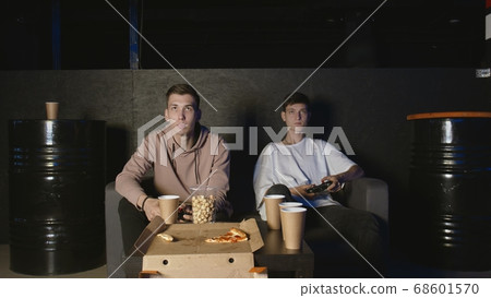 Two gamers in front of the screen are playing together in the online battle Two gamers in front of the screen are playing together in the online battle 68601570