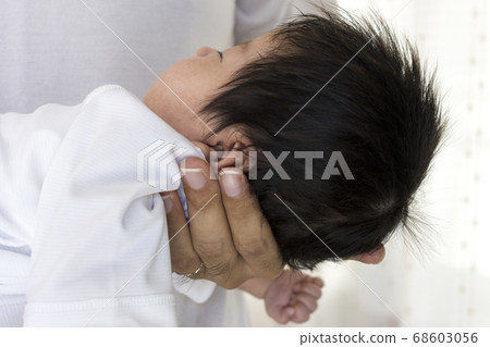 Hands of a man in his thirties supporting the neck of a newborn Hands of a man in his thirties supporting the neck of a newborn 68603056