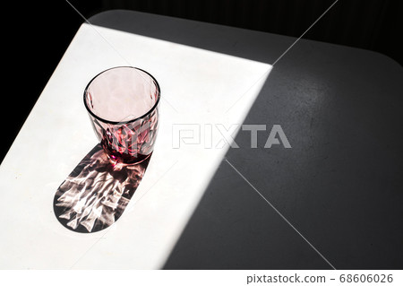Crystal red glass on white table. Hard shadows in sunlight. Crystal red glass on white table. Hard shadows in sunlight. 68606026