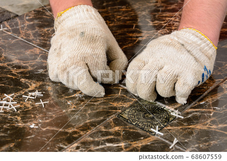 A man sets crosses between installed tiles 68607559