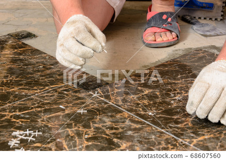 A man sets crosses between installed tiles 68607560