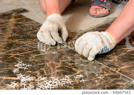 A man sets crosses between installed tiles 68607561