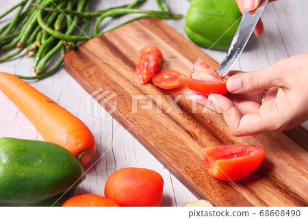 Hand Of Person Cutting Tomatoes On Chopping Board Hand Of Person Cutting Tomatoes On Chopping Board 68608490