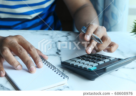 person hand using calculator and writing on notebook person hand using calculator and writing on notebook 68608976