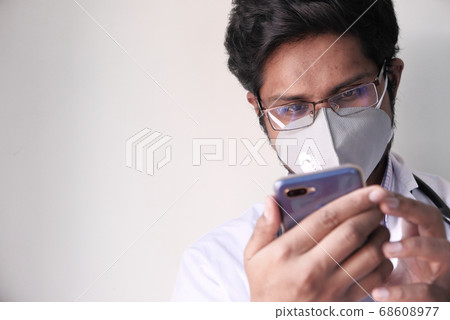 Male doctor in white coat is using a modern smartphone device Male doctor in white coat is using a modern smartphone device 68608977