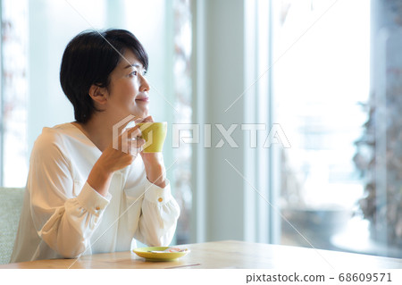 Woman in her 40s drinking coffee in the living room Woman in her 40s drinking coffee in the living room 68609571