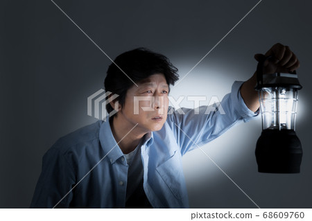 Middle-aged man looking for an exit with a lantern in the dark world Middle-aged man looking for an exit with a lantern in the dark world 68609760
