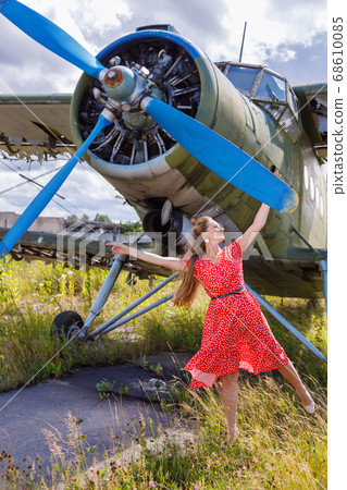 Young woman in a red pin up style dress stands by Young woman in a red pin up style dress stands by 68610085