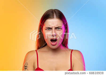 Caucasian young woman's portrait on gradient studio background in neon 68610939