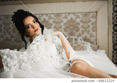 Gorgeous bride in robe posing and preparing for the wedding ceremony face in a room Gorgeous bride in robe posing and preparing for the wedding ceremony face in a room 68611224