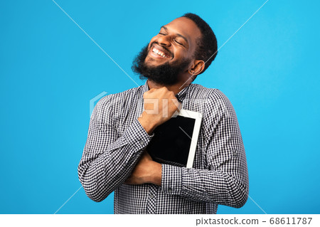 Smiling african american guy holding digital tablet Smiling african american guy holding digital tablet 68611787