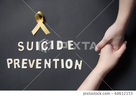 World suicide prevention day. Holding hands for helping and supporting depressed woman with yellow ribbon awareness and SUICIDE PREVENTION wooden word on black background. Mental health care concept. World suicide prevention day. Holding hands for helping and supporting depressed woman with yellow ribbon awareness and SUICIDE PREVENTION wooden word on black background. Mental health care concept. 68612153