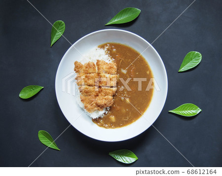 Top view of Japanese fried fish curry rice on white plate with dirty dark background and green leave herbs. Asian food concept. Top view of Japanese fried fish curry rice on white plate with dirty dark background and green leave herbs. Asian food concept. 68612164