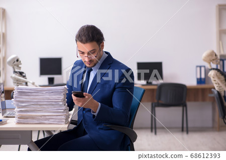 Young male employee with skeletons in the office Young male employee with skeletons in the office 68612393