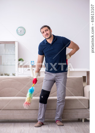 Young leg injured contractor cleaning the house 68613107