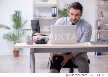 Young leg injured employee working in the office Young leg injured employee working in the office 68613183
