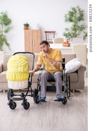 Young man contractor in wheel-chair looking after newborn 68613234