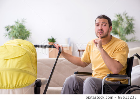 Young man contractor in wheel-chair looking after newborn 68613235