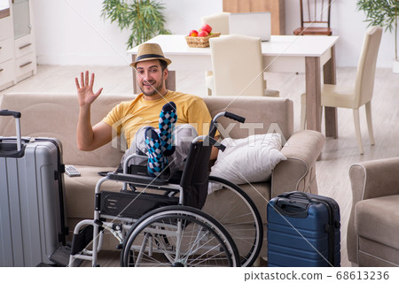 Young man in wheel-chair preparing for departure at home 68613236