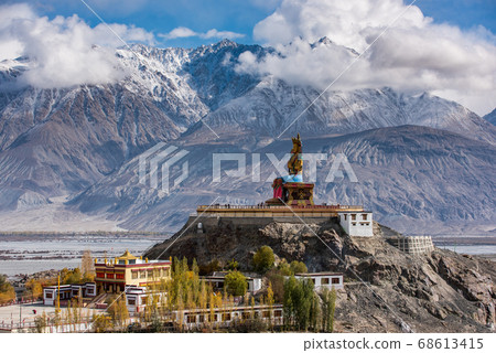 The Maitreya Buddha statue with Himalaya mountains in the background from Diskit Monastery or Diskit Gompa, Nubra valley, Leh Ladakh The Maitreya Buddha statue with Himalaya mountains in the background from Diskit Monastery or Diskit Gompa, Nubra valley, Leh Ladakh 68613415