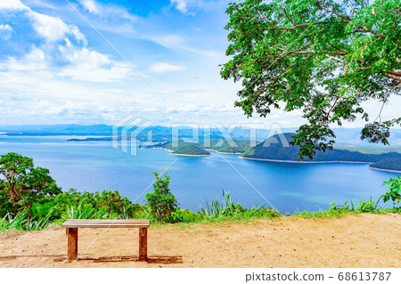 Lookout point with resting wooden bench. Beautiful scenery of nature with a large reservoir above the Srinagarind Dam at Rai Ya Yam view point in Si Sawat District, Kanchanaburi Thailand. Lookout point with resting wooden bench. Beautiful scenery of nature with a large reservoir above the Srinagarind Dam at Rai Ya Yam view point in Si Sawat District, Kanchanaburi Thailand. 68613787