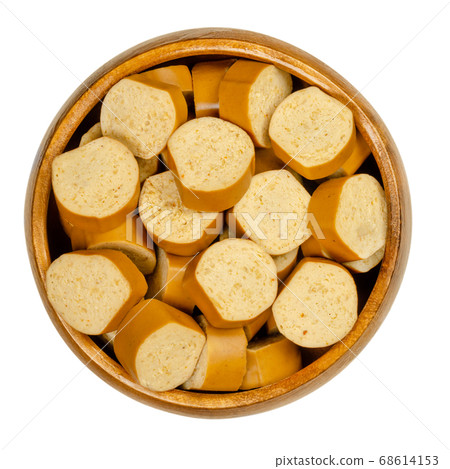 Slices of vegan Vienna sausages in a wooden bowl. Parboiled sausages, made of tofu, smoked at low temperature. Also called Wiener or Frankfurter Wuerstl. Close-up, from above, over white, food photo. 68614153