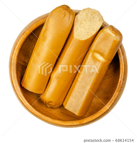 Vegan Vienna sausages in wooden bowl. Thin parboiled sausages, made of tofu then given a low temperature smoking. Also called Wiener or Frankfurter Wuerstl. Close-up from above over white, food photo. 68614154